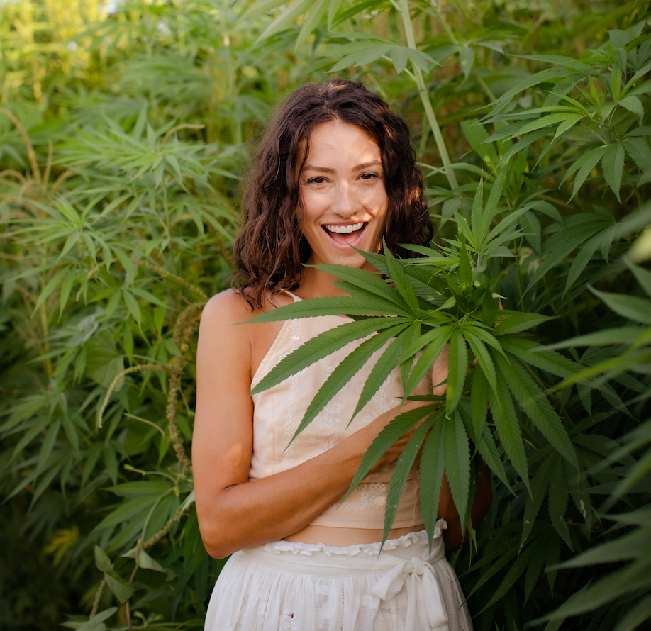 smiling woman facing camera, standing in a hemp field.